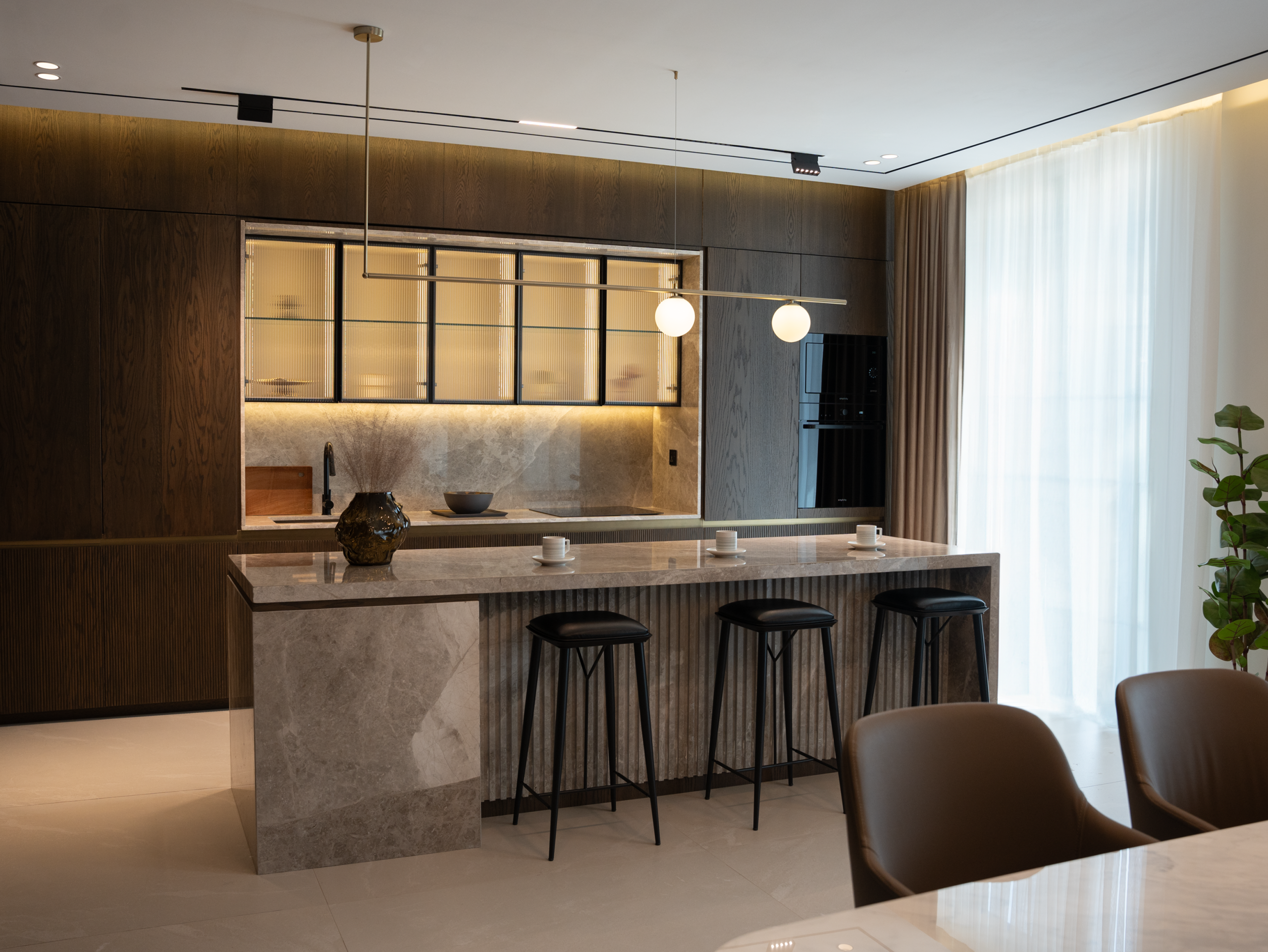 Sleek modern kitchen with marble island and stylish lighting.
