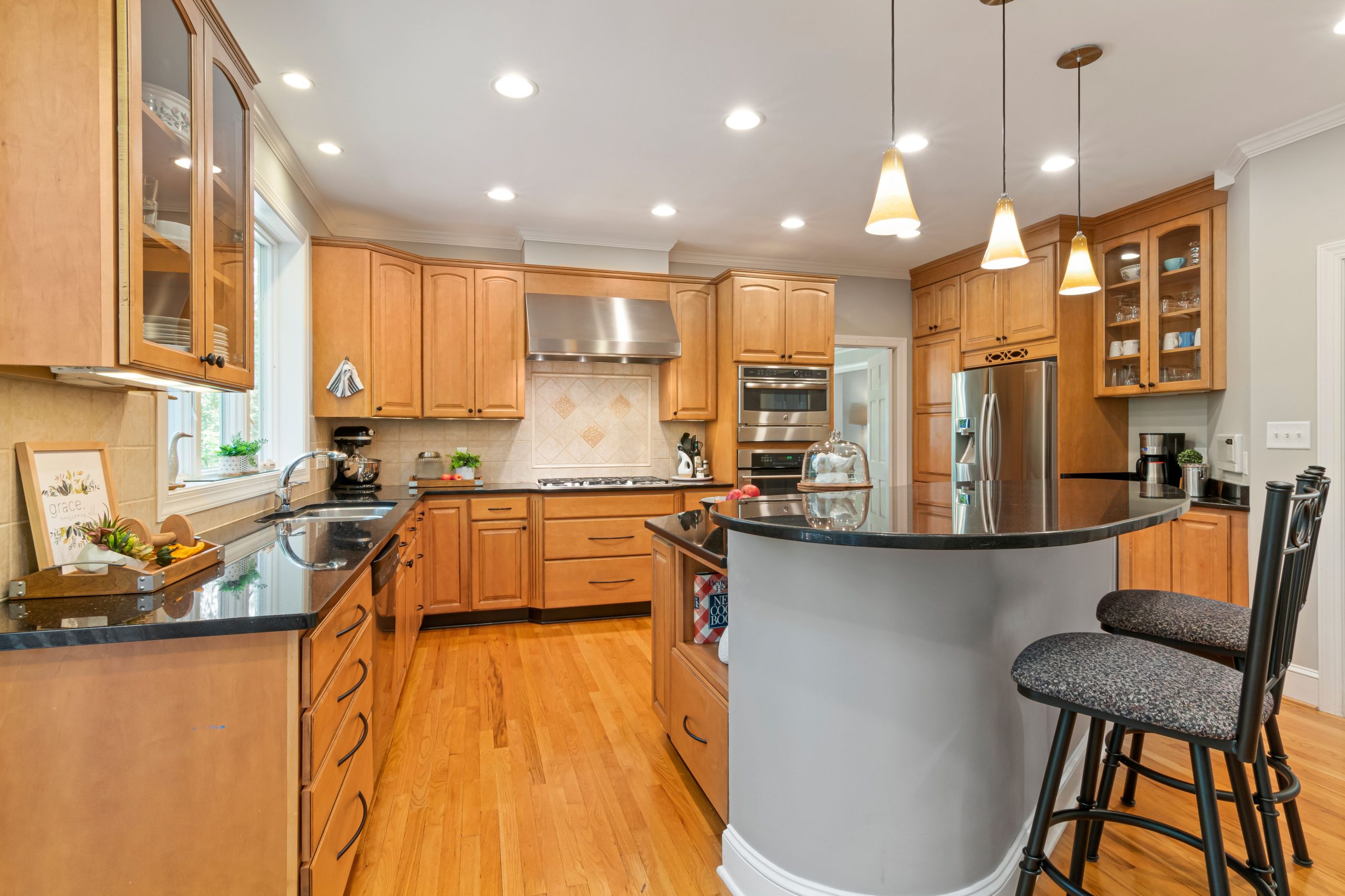Spacious modern kitchen featuring wooden cabinets, island, and stainless steel appliances.