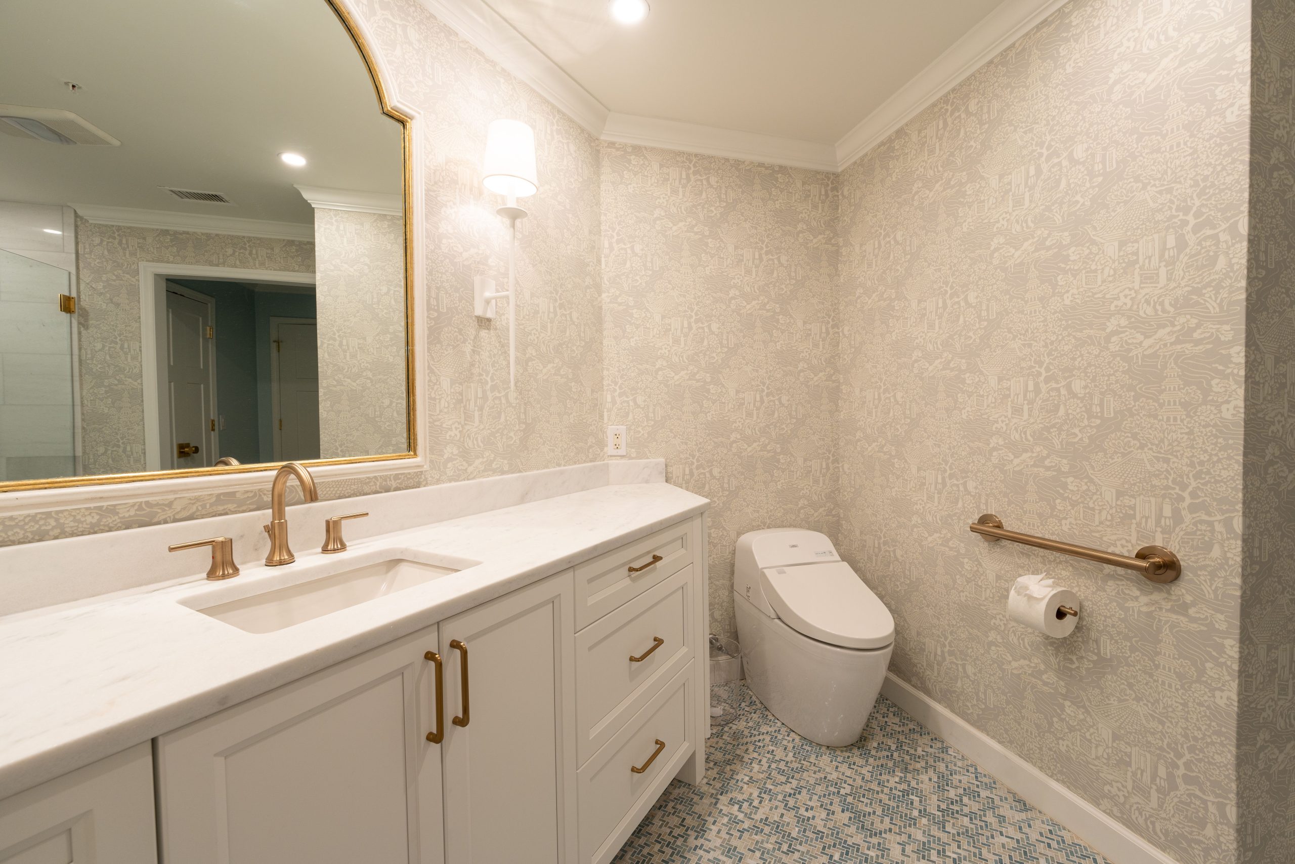 Stylish bathroom design featuring a vanity, mirror, modern toilet, and patterned wallpaper.