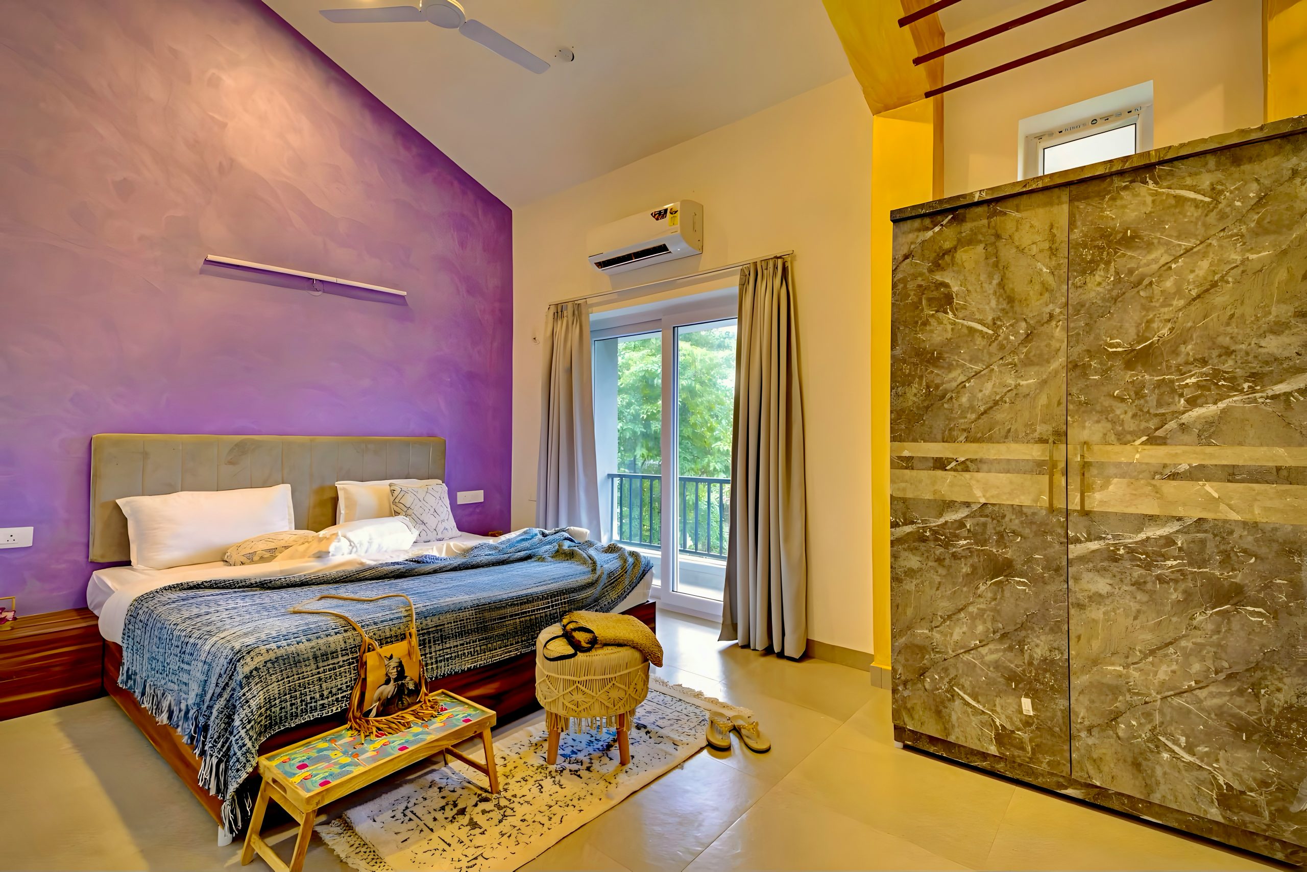 Stylish bedroom with large bed, purple accent wall, and balcony.