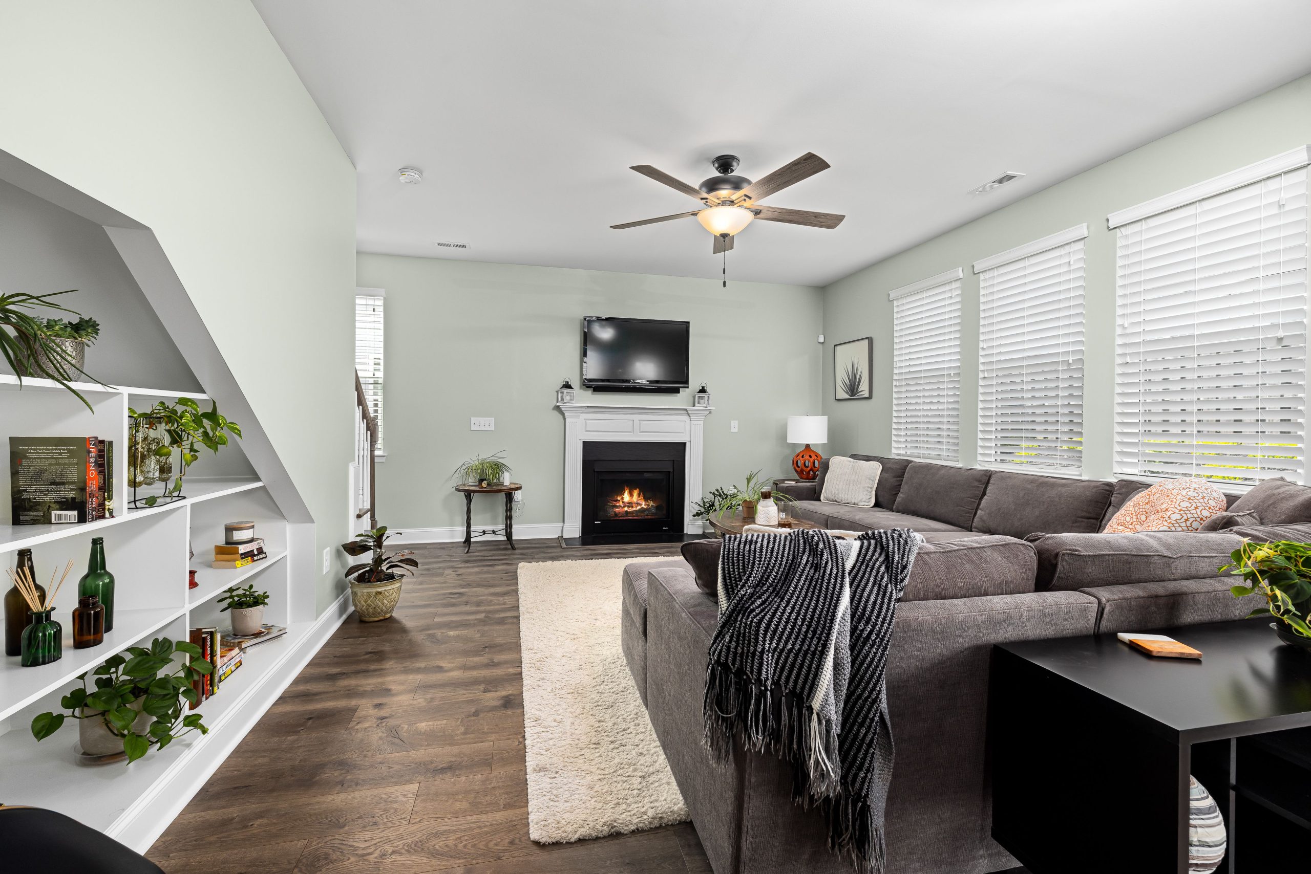 Stylish living room featuring a large sectional sofa, fireplace, and indoor plants for a cozy ambiance.