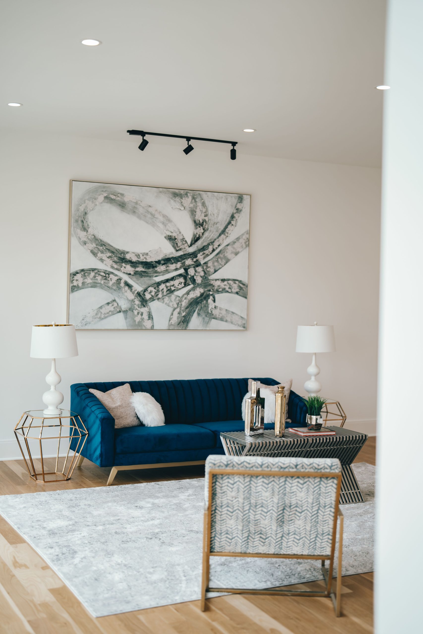 Stylish living room interior featuring a blue sofa, abstract artwork, and decorative lamps.