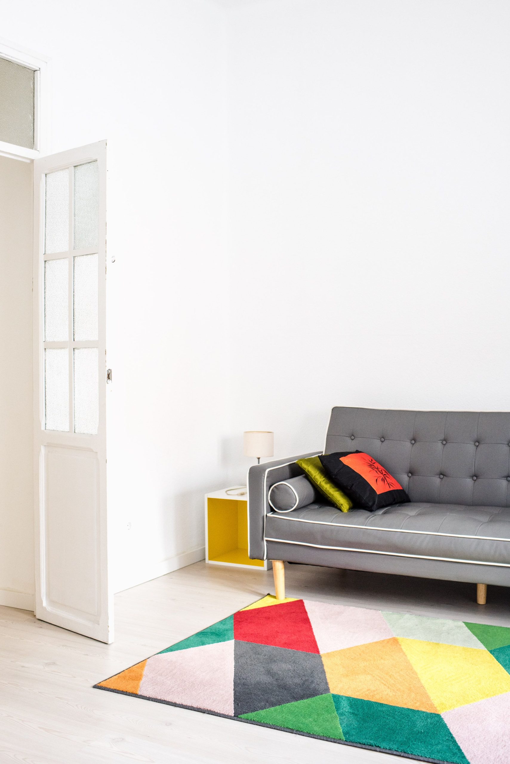 Stylish minimalist living room featuring a colorful geometric rug and a cozy grey sofa for a chic home interior.