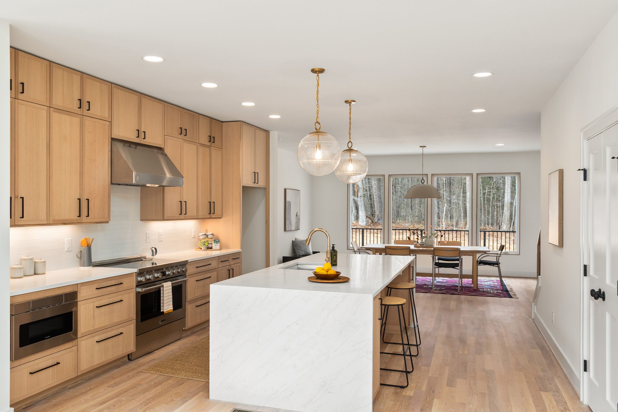 Stylish open concept kitchen featuring a marble island and wooden cabinets with a dining space.