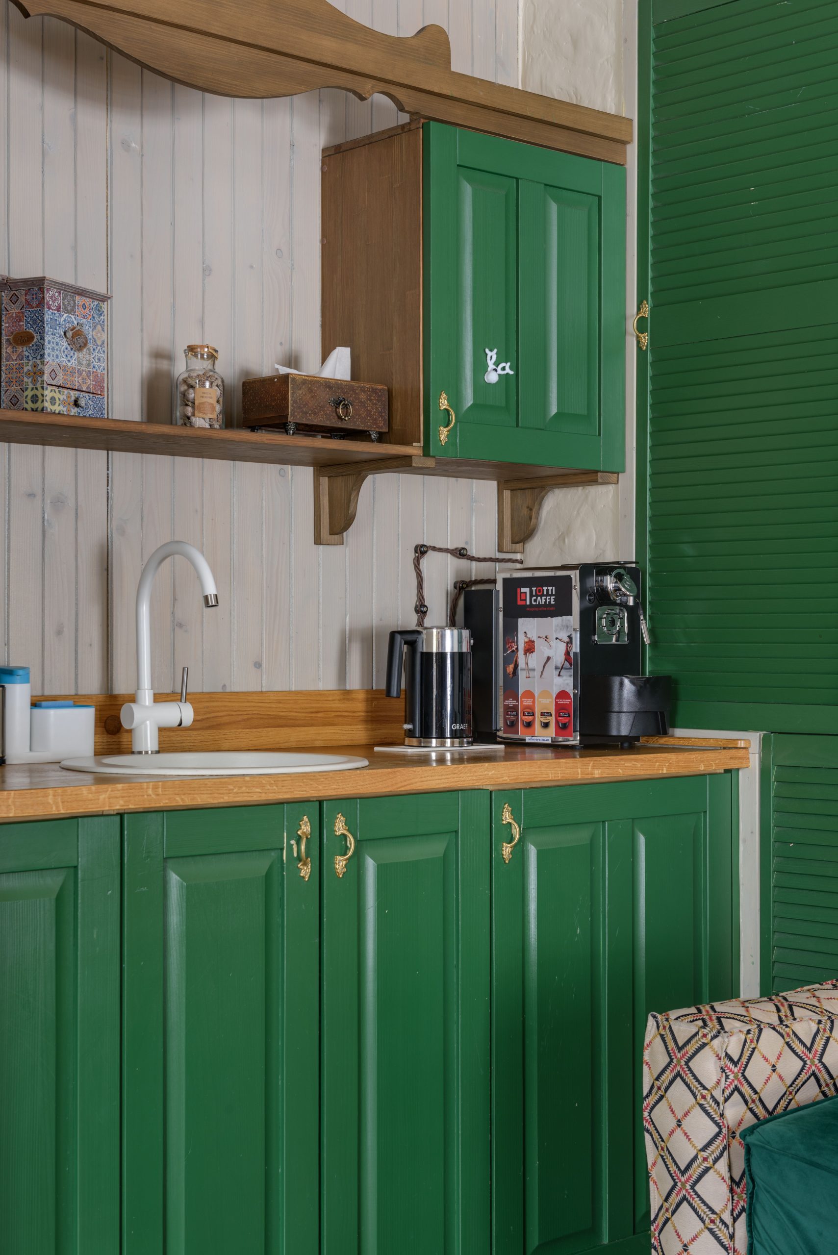 Vintage kitchen scene with green cabinets, coffee maker, and sink, showcasing charming details.