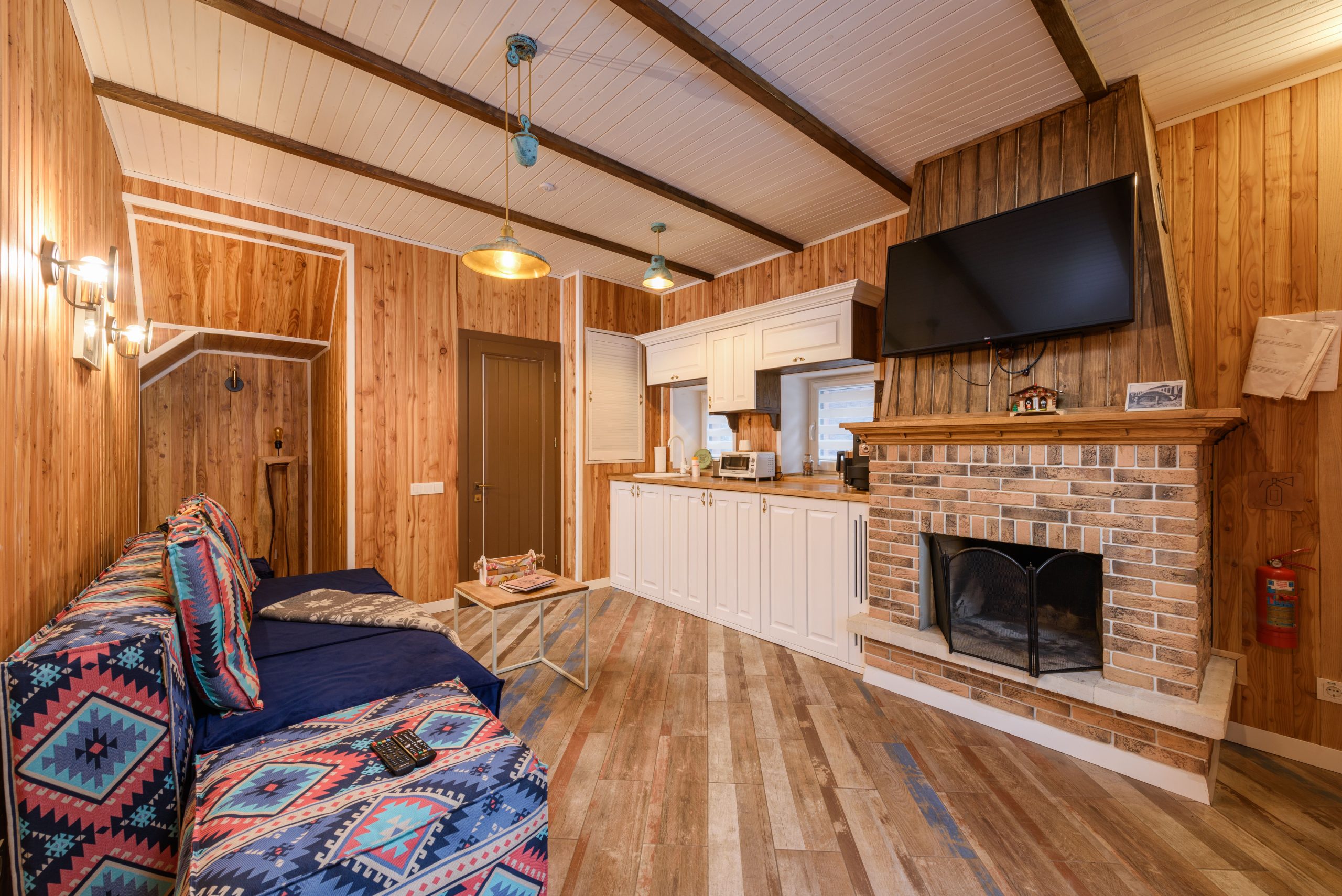 Warm rustic living room featuring wooden walls, a brick fireplace, and cozy seating area with modern amenities.