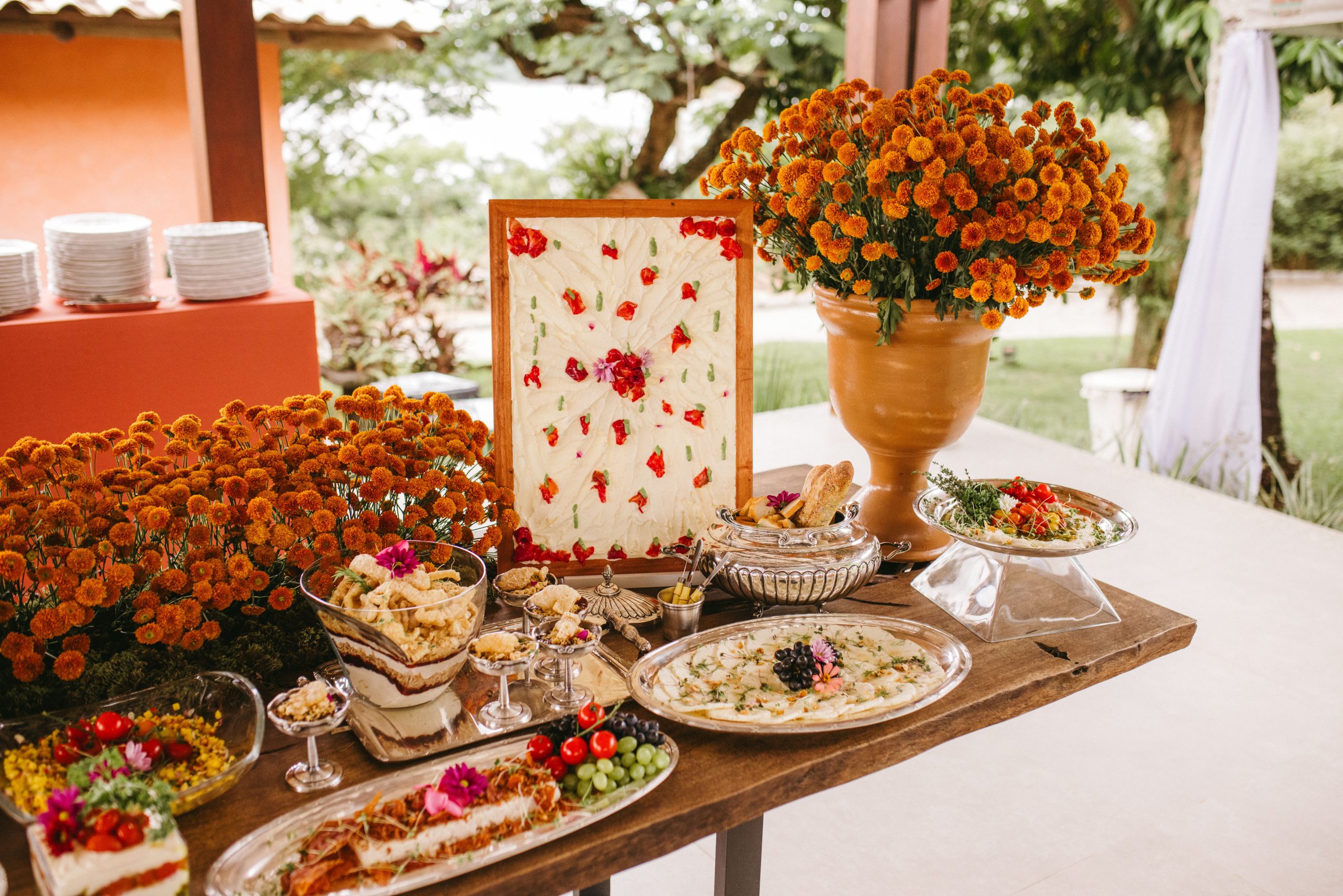Wedding buffet setup with vibrant floral decor and diverse dishes, perfect for outdoor events.