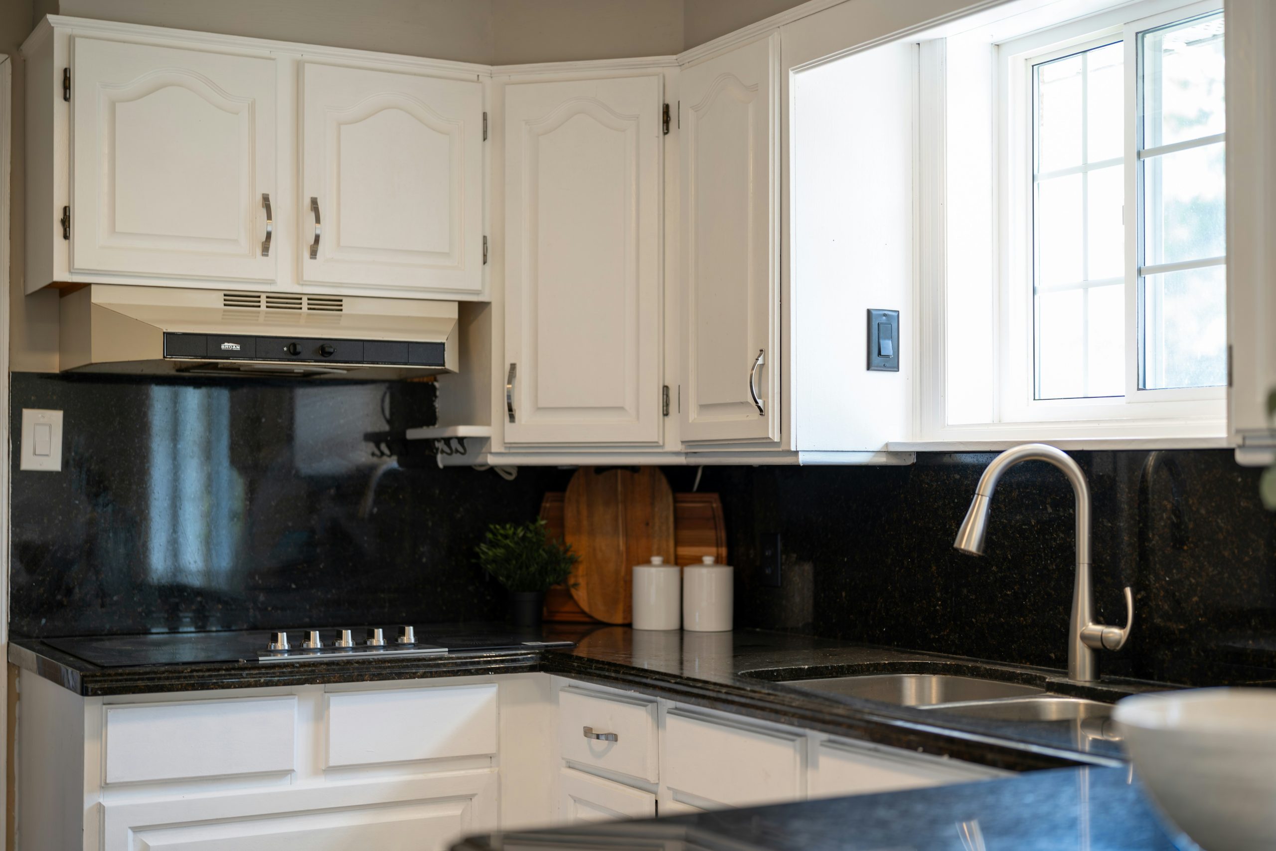 A modern kitchen with white cabinets and granite countertops.